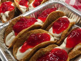 Mini strawberry cheesecake tacos with crisp graham-coated shells, cheesecake filling, and strawberry topping