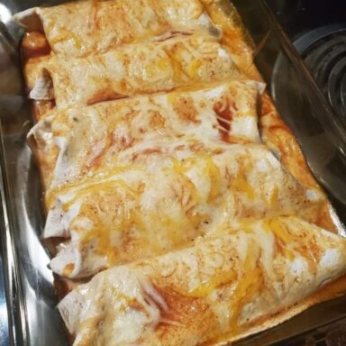 Baked cream cheese chicken enchiladas with melted cheese and green chile sauce