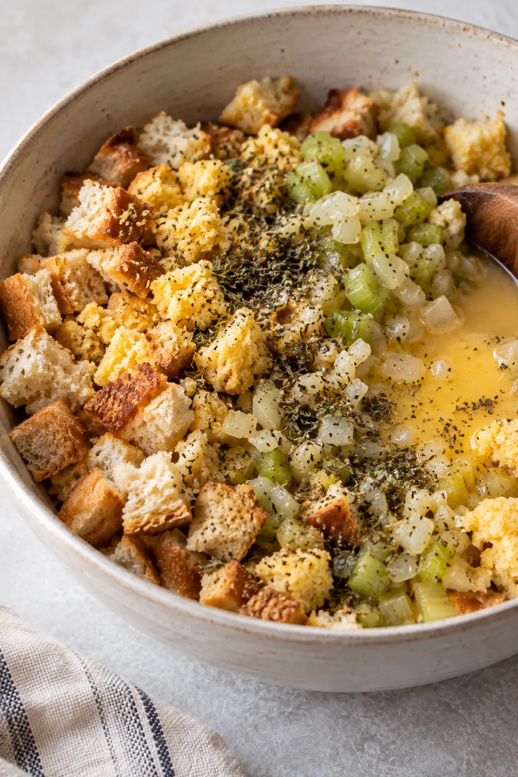 Bread and cornbread stuffing mixture with sauteed onion, celery, herbs, egg, and broth