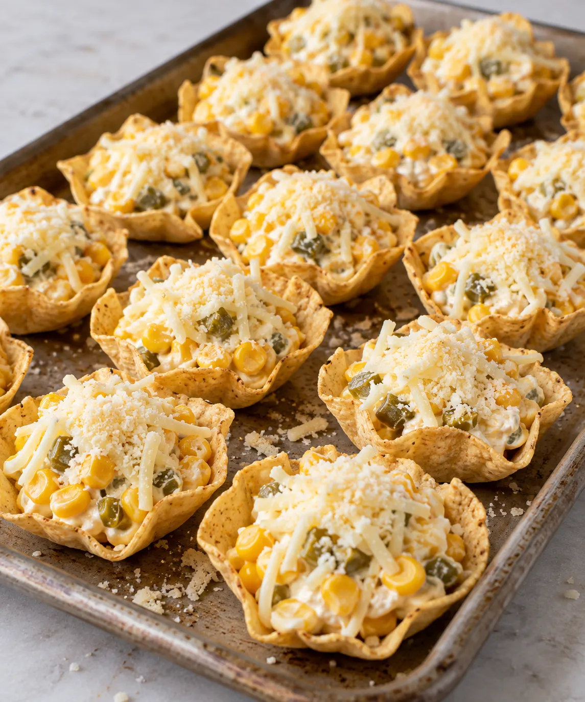Filled tortilla scoops topped with mozzarella and Parmesan before baking