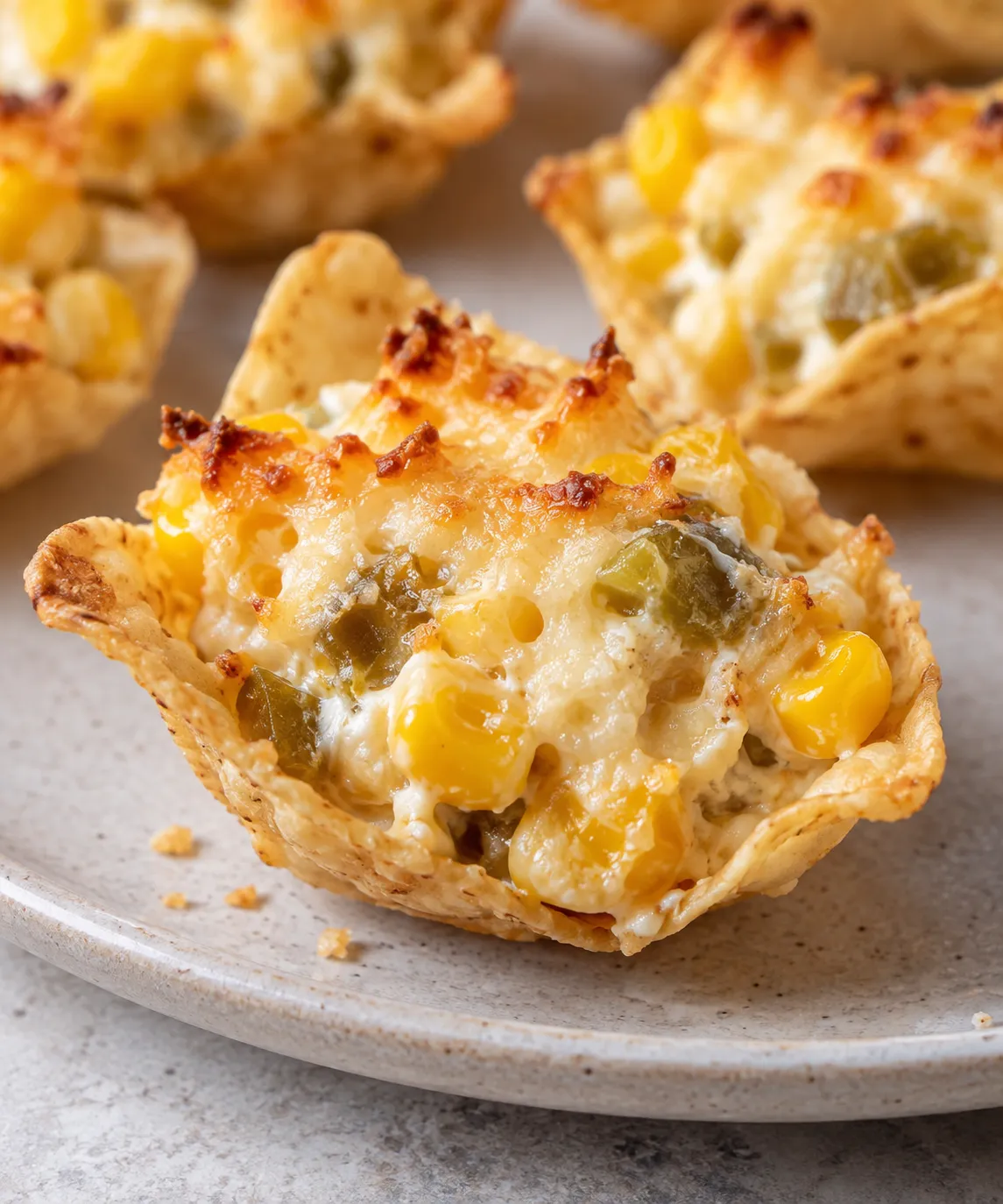 Close-up of one crispy tortilla cup filled with creamy corn, green chiles, and browned cheese