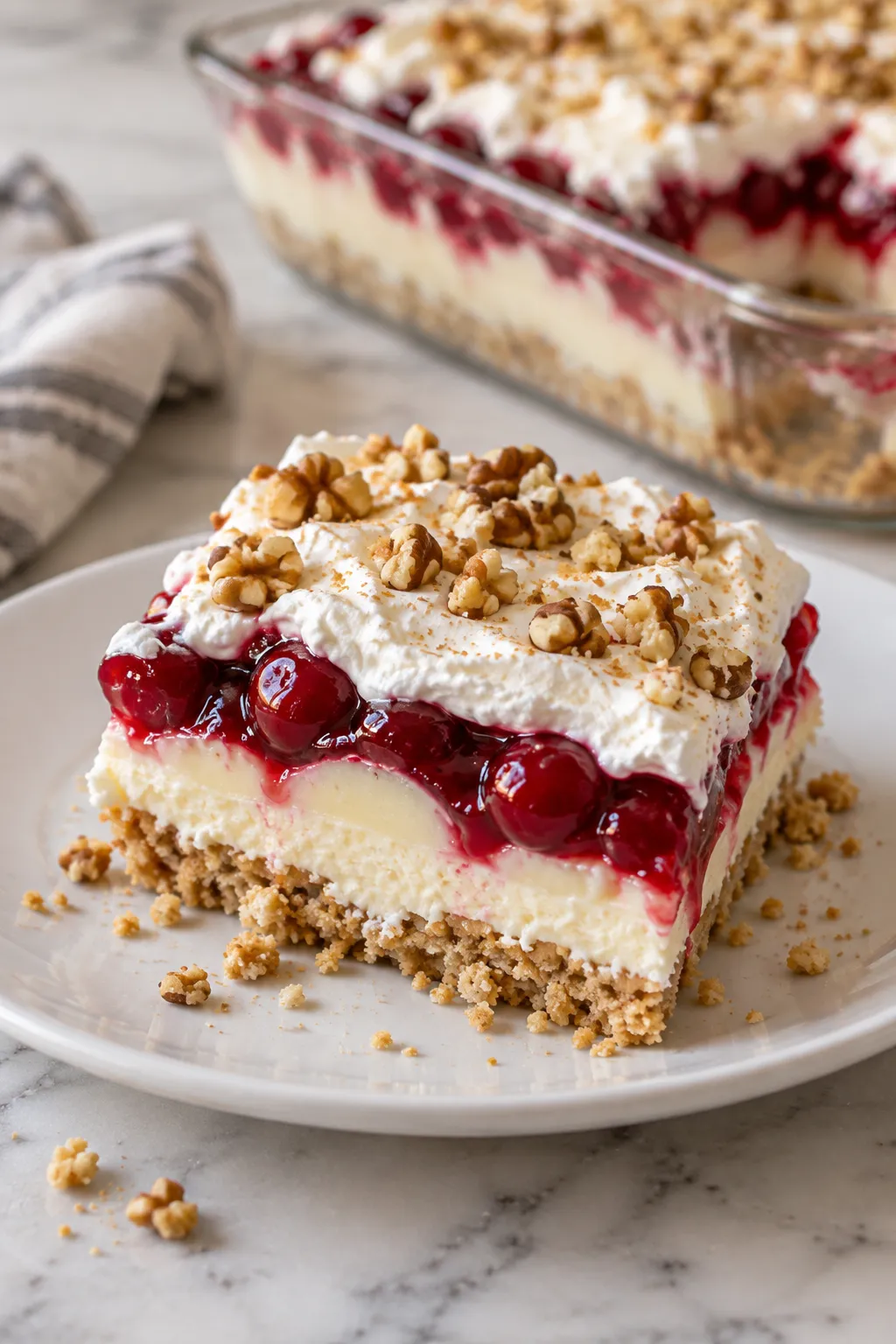 Slice of no-bake cherry cheesecake lush showing cookie, cream, pudding and cherry layers
