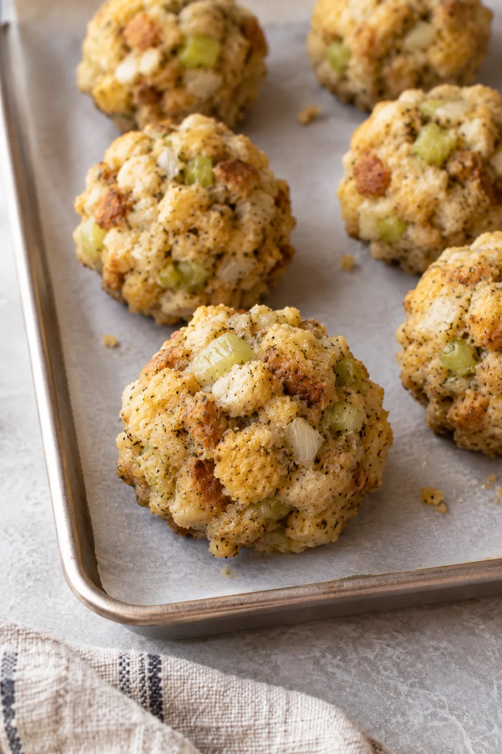 Unbaked stuffing balls shaped and arranged on a parchment-lined baking sheet