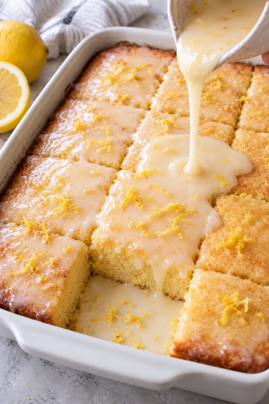 Lemon glaze being poured over Lemon Cake To Die For in a baking dish