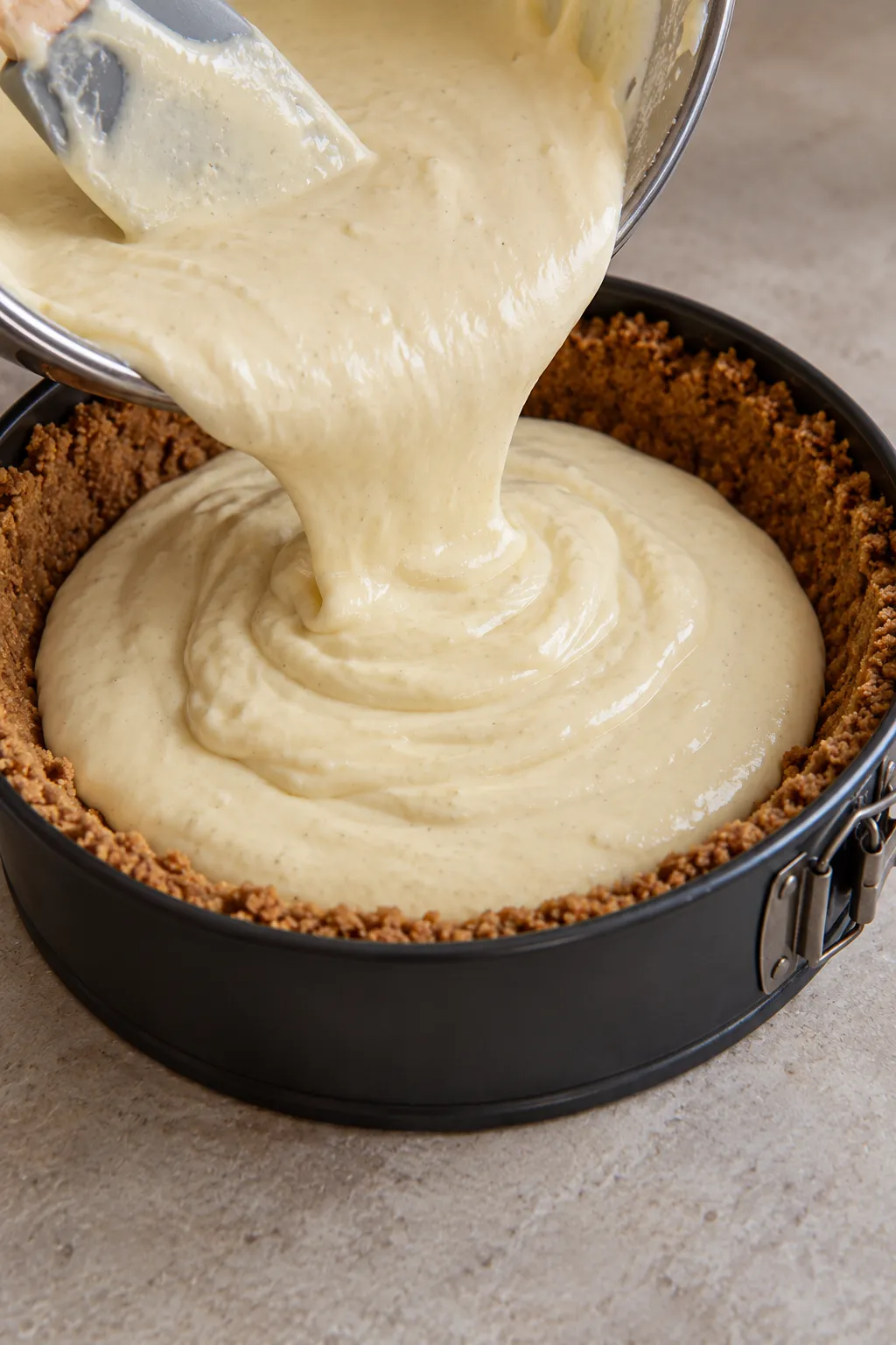 Cheesecake batter poured into graham cracker crust for pecan cheesecake pie