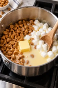 Peanut butter chips, marshmallows, condensed milk, and butter melting in a saucepan for homemade Payday candy bars