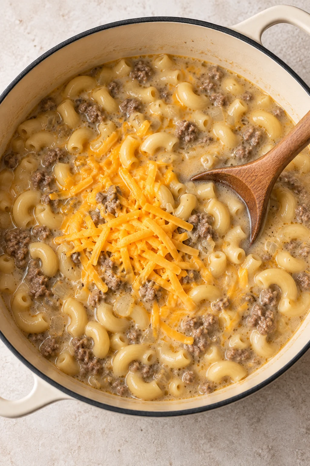 Shredded cheddar melting into creamy ground beef and macaroni soup