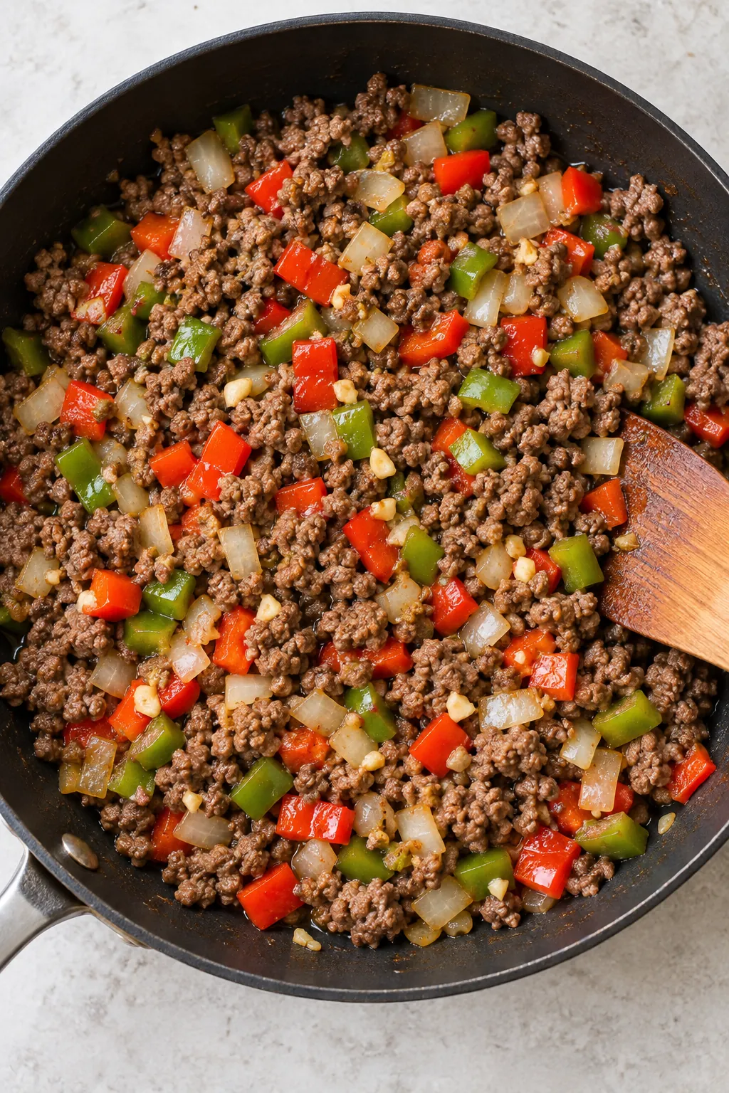 Browned ground beef with chopped red and green peppers, onion, and garlic in a skillet