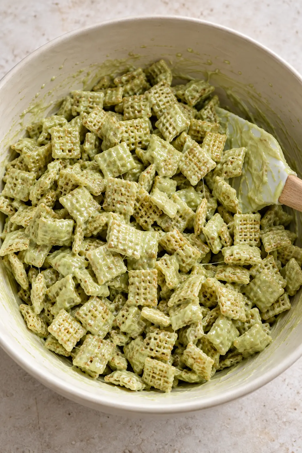 Rice Chex cereal gently folded with pistachio white chocolate coating before powdered sugar is added