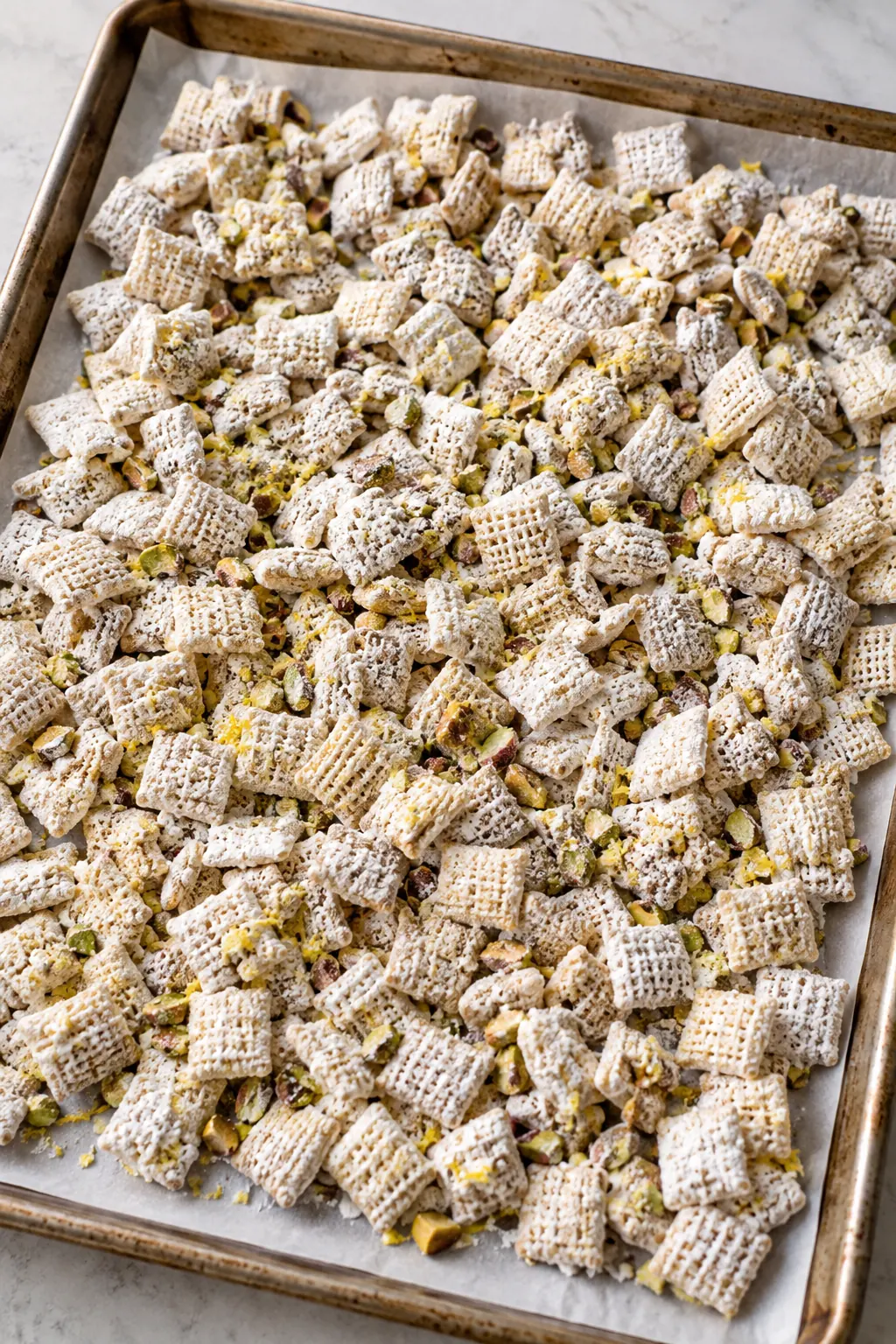 Pistachio lemon puppy chow spread on parchment to set before serving