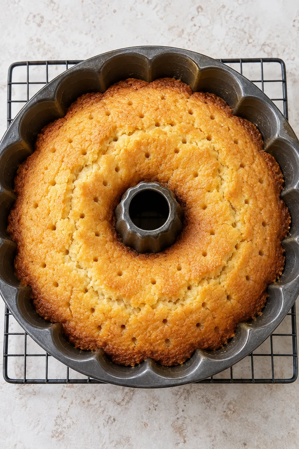 Baked butter cake in a Bundt pan with small holes ready for the warm butter sauce