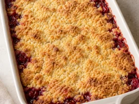 Whole cherry dessert with a golden cake-mix topping in an ivory baking dish