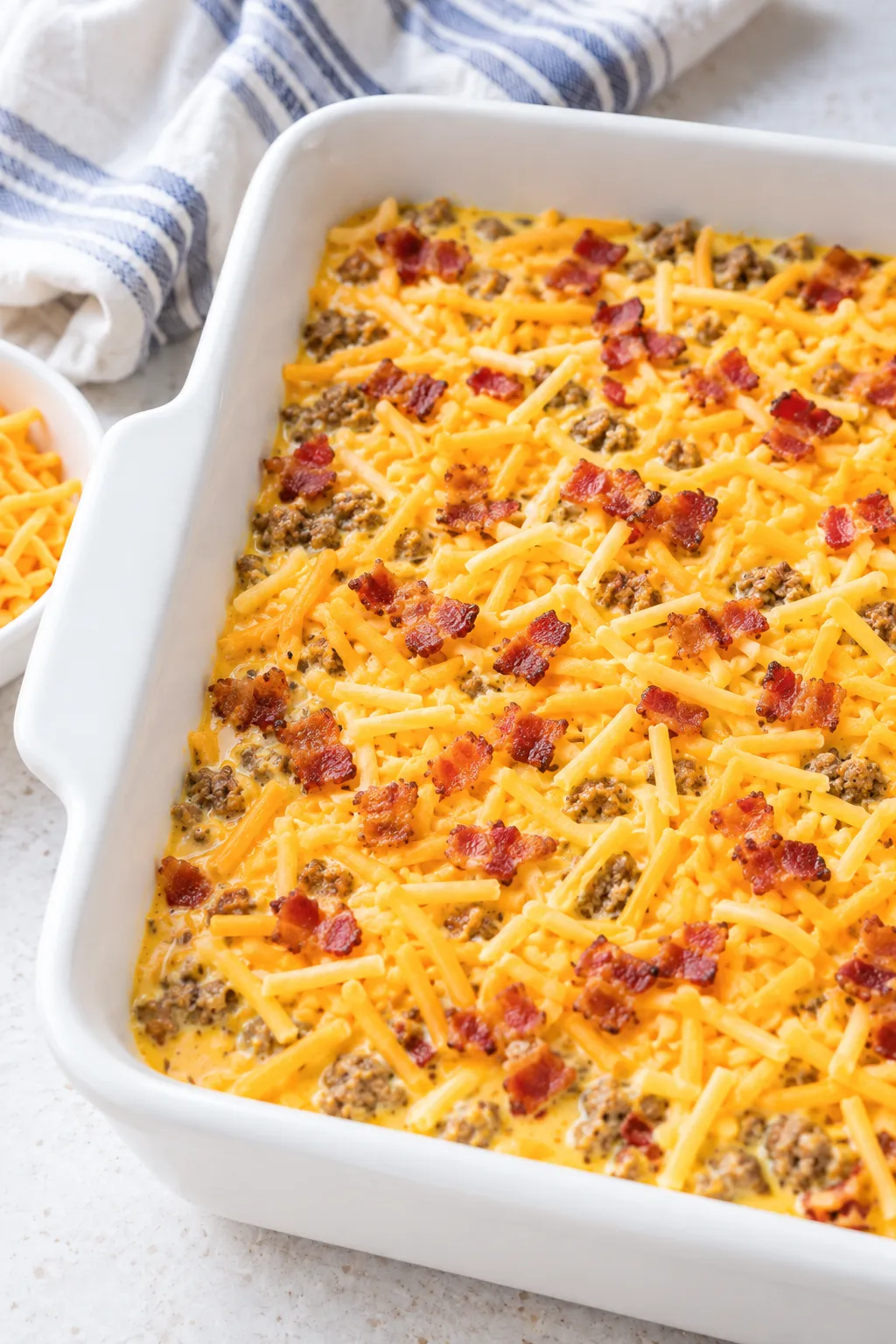 Low-Carb Bacon Cheeseburger Casserole assembled with cheddar before baking