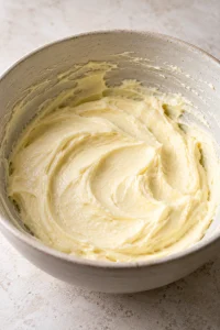 Pale cream cheese filling beaten smooth in an oatmeal mixing bowl
