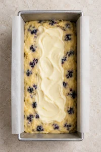 Cream cheese filling spooned along the center of the blueberry batter