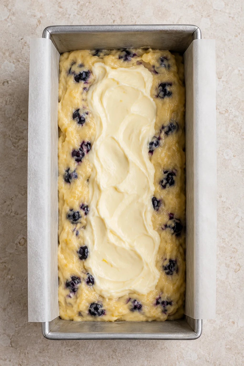 Cream cheese filling spooned along the center of the blueberry batter