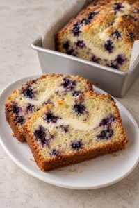Slices of blueberry loaf showing berries and an irregular baked cream cheese swirl