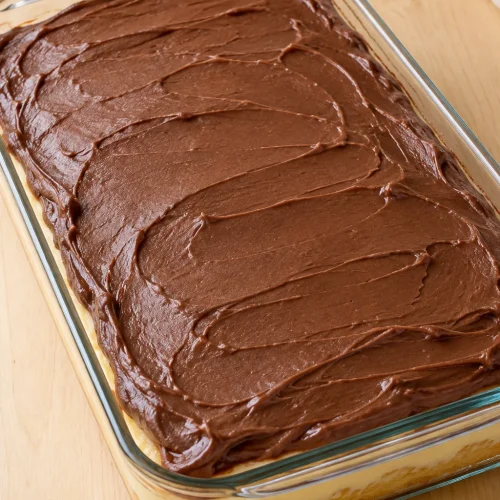 Whole Boston cream poke cake with chocolate frosting in a glass baking dish