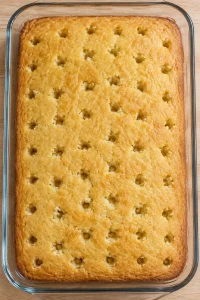 Round holes spaced across a cooled yellow cake for pudding filling
