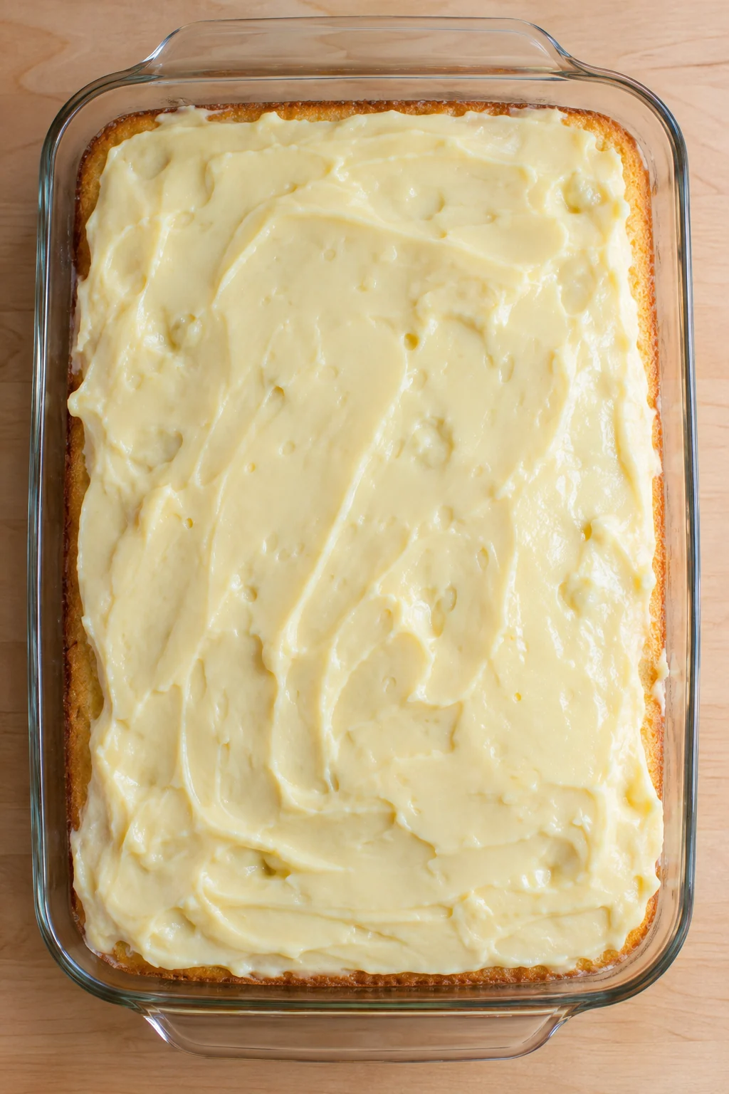 Vanilla pudding spread across the top of the poked yellow cake