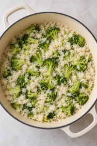 Tender long-grain rice and cooked broccoli florets in the pot before the creamy filling is mixed