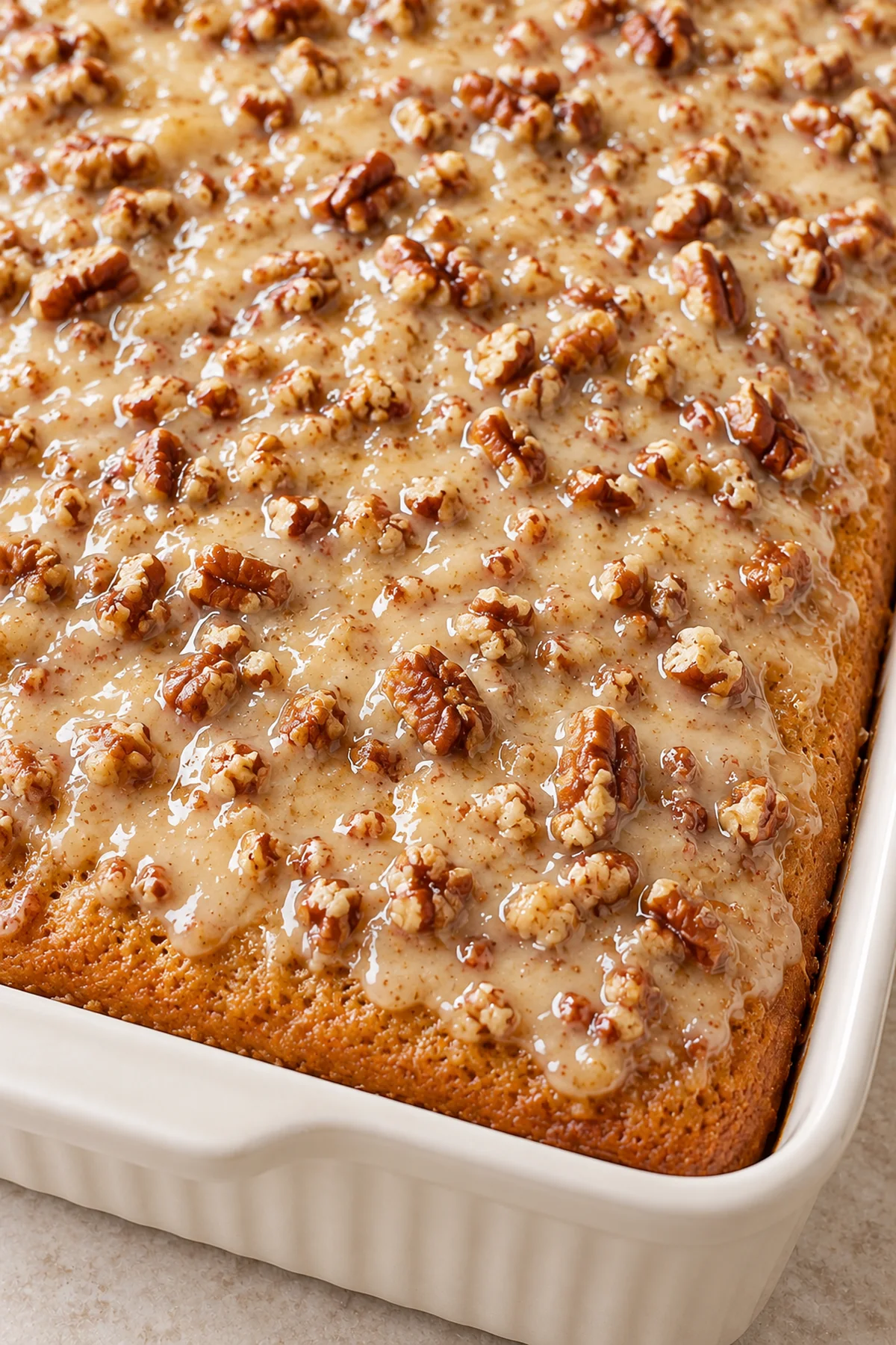 Close-up of chopped pecans in the butter and sweetened condensed milk glaze on the cake