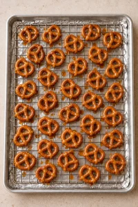 Warm toffee-coated mini pretzel twists spaced on the prepared rack before oven drying