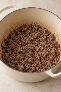 Browned ground beef crumbles in a Dutch oven.