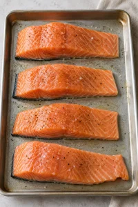 Raw salmon fillets lightly oiled and seasoned with salt and pepper