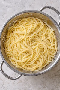 Cooled and drained spaghetti in a metal colander