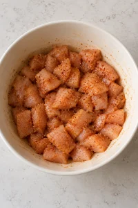 Small chicken pieces coated with garlic, onion and paprika seasoning in a mixing bowl