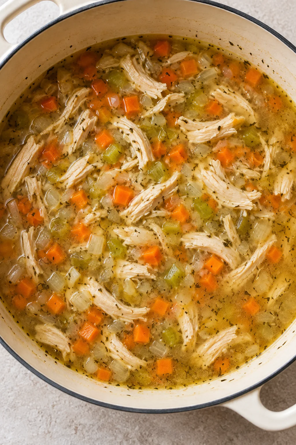 Shredded chicken returned to the broth with softened carrots, celery, and onion.