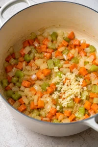 Minced garlic added to the softened onion, carrots, and celery.