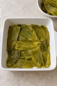 Drained whole green chiles opened flat across the bottom of a square baking dish