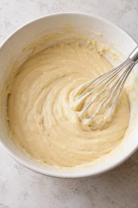 Smooth pale vanilla cake batter mixed in a white bowl