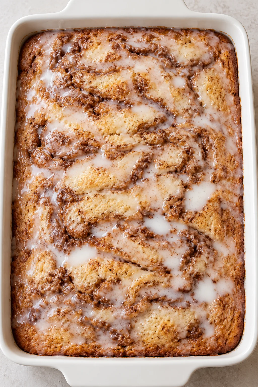 Thin vanilla glaze spread over the baked cinnamon swirl cake