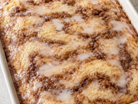 Whole glazed Cinna-bun cake with brown cinnamon swirls in a baking dish