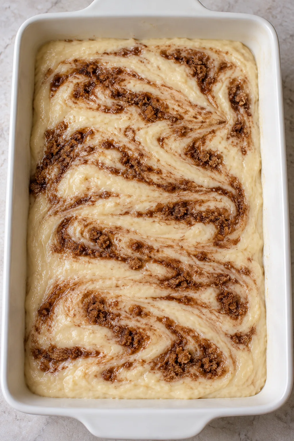 Brown cinnamon ribbons gently swirled through raw vanilla cake batter