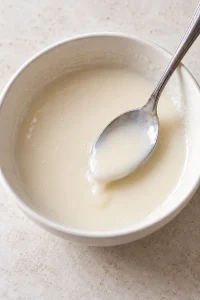 Pourable vanilla glaze made with powdered sugar and milk in a small bowl