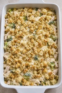 The unbaked casserole covered with creamy sauce and the reserved buttered stuffing.