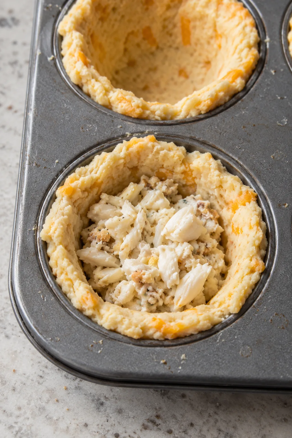 Chunky crab filling spooned into an open cheddar biscuit dough cup