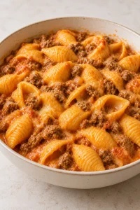 A cream bowl of medium pasta shells with ground beef and creamy cheese sauce