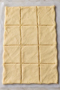One rectangle of crescent dough cut into 12 pieces after sealing the seams