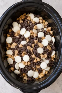 Unmelted chocolate chips, peanut butter chips, and white wafers layered over peanuts