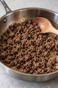 Ground beef browned into small crumbles in a skillet.