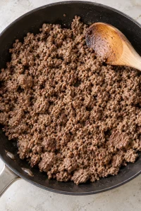 Ground beef browned into small crumbles in a skillet before adding the filling ingredients