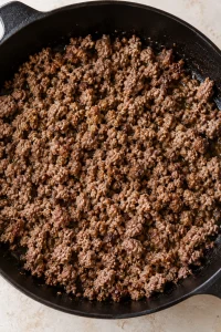 Ground beef browned in a skillet for stuffed pepper casserole.
