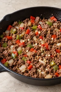 Minced garlic added to the beef, onion and bell pepper mixture.