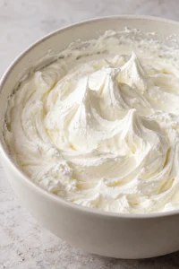 Whipped cream with standing peaks, prepared for folding into the filling and topping the pie.