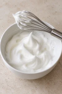 Egg whites beaten to stiff peaks in a mixing bowl.